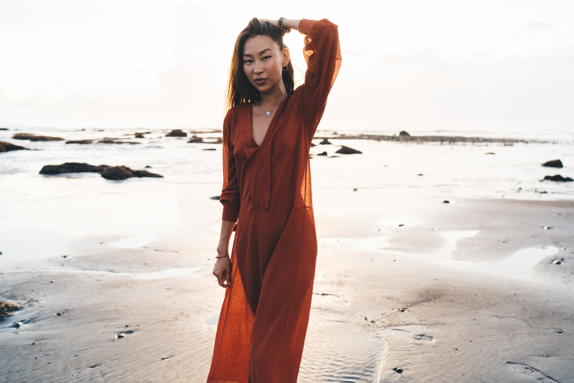 Young model in long light rust colored dress on beach